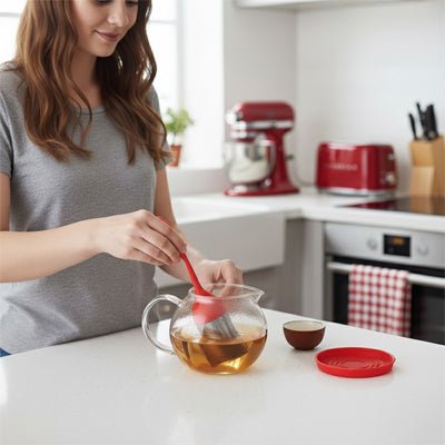 femme tenant infuseur  a the rouge main droite